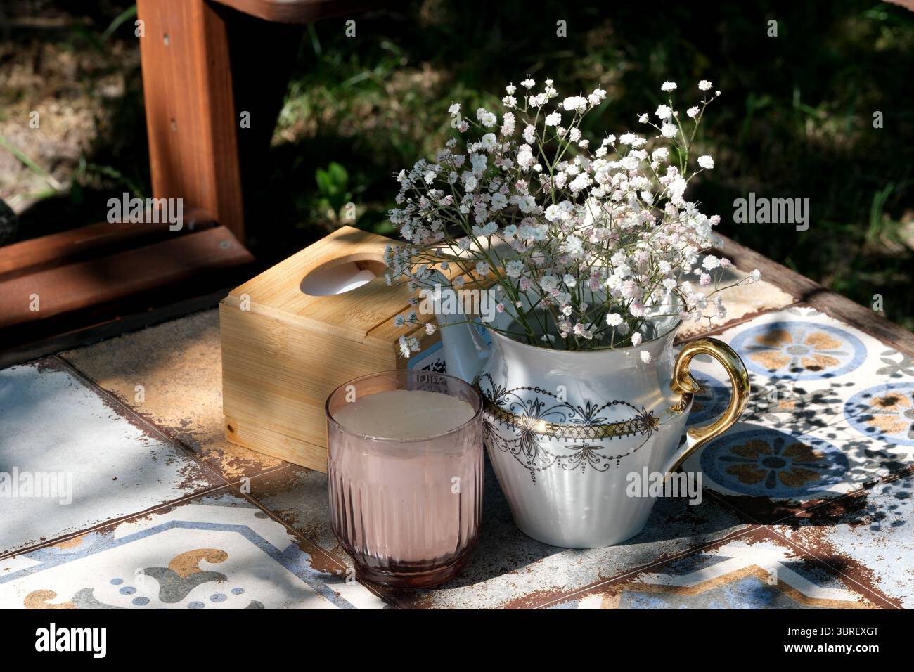 Eine bezaubernde Tasse Tee und frische Blumen sorgen für eine ruhige Atmosphäre im Freien. Stockfoto