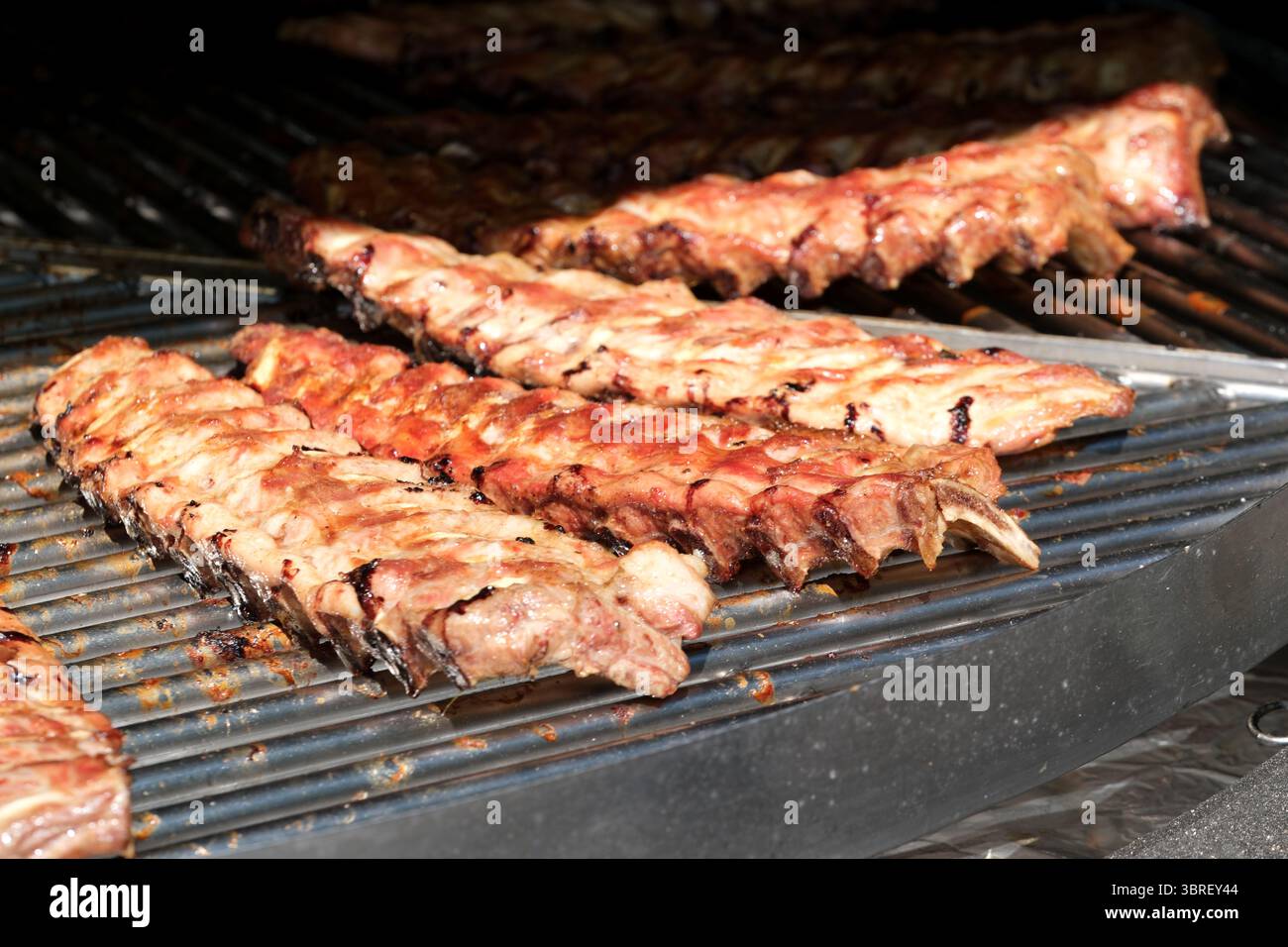 Saftige Schweinerippchen kochen über heißen Flammen und strahlen unter der Sonne köstliche Aromen aus. Stockfoto