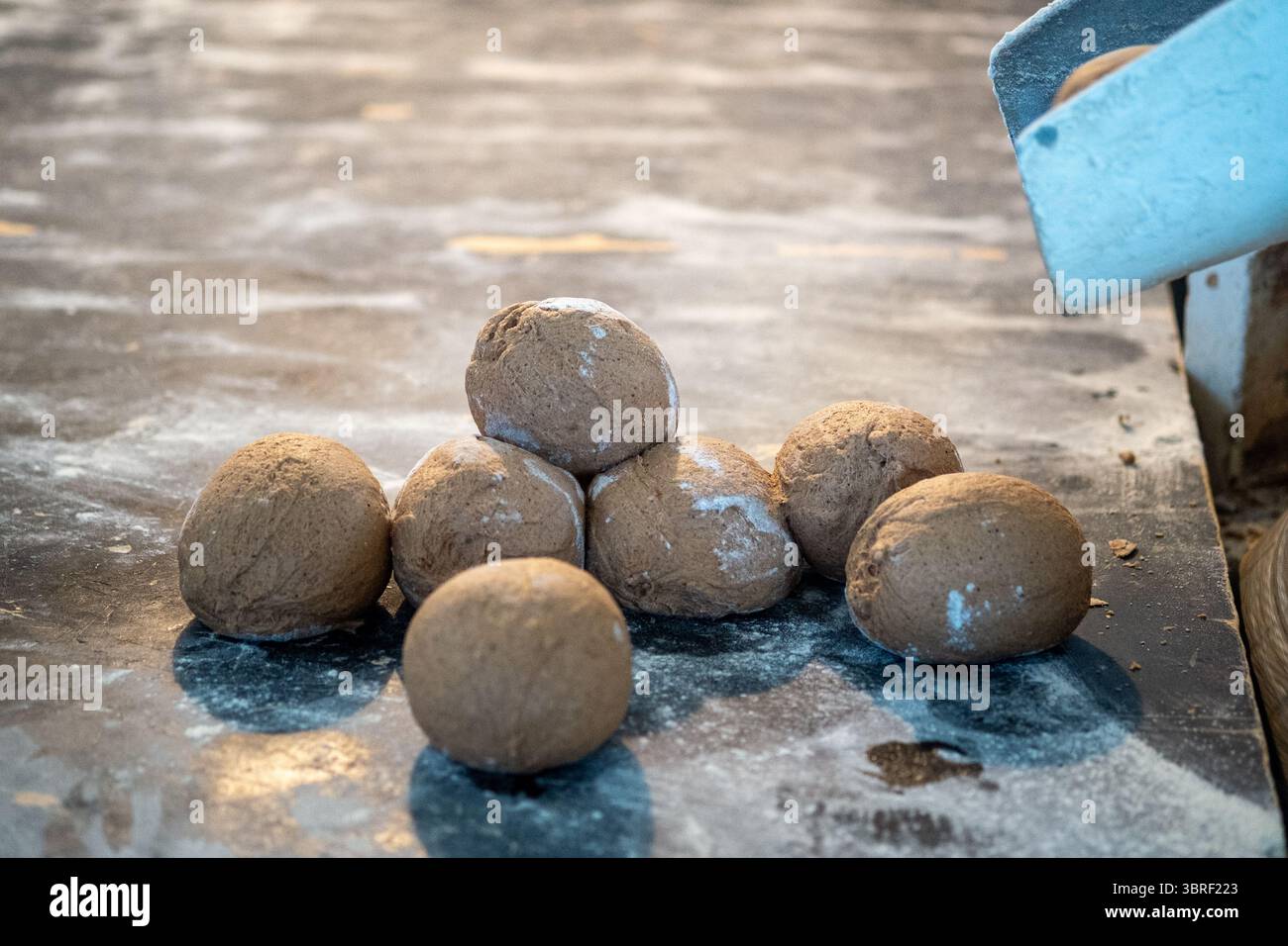 Ungebackene Teigkugeln auf bemehlter Oberfläche in der Bäckerei Stockfoto