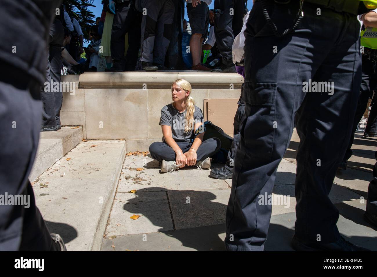 Ein verhafteter Unterstützer der Palästinensischen Aktion sitzt während der Kundgebung unter den Polizeibeamten der Metropolitanen. Anhänger der kürzlich verordneten Terrororganisation Palästinensische Aktion protestierten auf dem Parliament Square Westminster. Da die Gruppe als terroristische Bedrohung eingestuft wird, kann jeder, der Unterstützung zeigt, verhaftet und verfolgt werden. Stockfoto