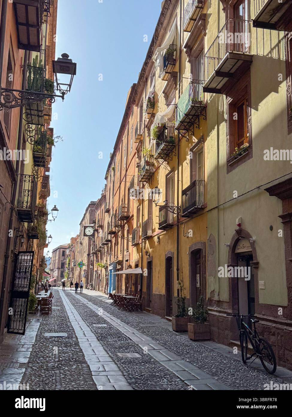Die kopfsteingepflasterte Straße, die von farbenfrohen historischen Gebäuden in Europa gesäumt ist, bietet eine ruhige Tagesszene mit Menschen, die gemütlich, Vintage schlendern Stockfoto