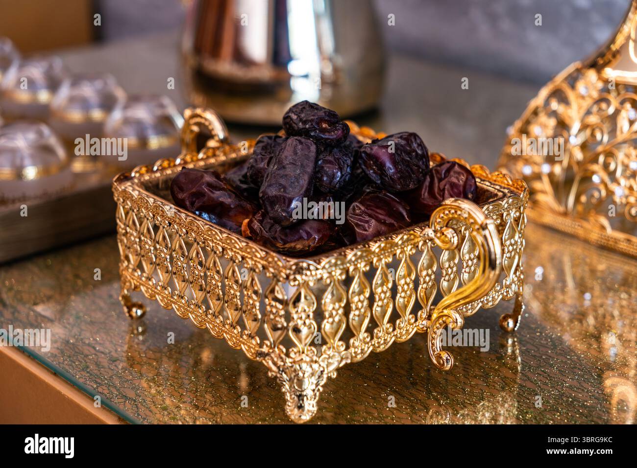 Frische Datteln in einer eleganten goldenen Box auf einem Tisch. Traditionelle Früchte aus dem Nahen Osten werden oft während des Ramadan und bei festlichen Feierlichkeiten verwendet. Köstlich Stockfoto