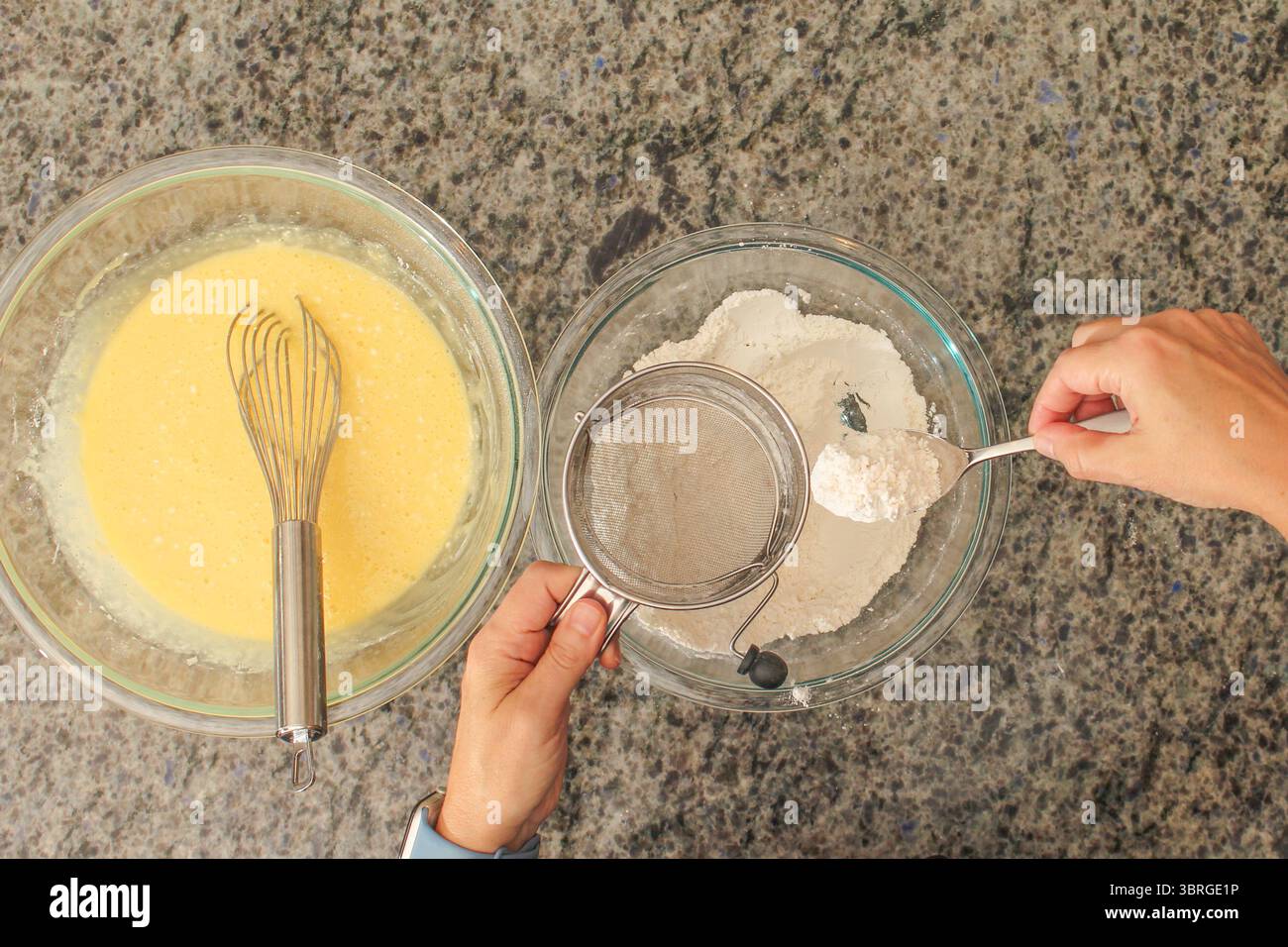 Überkopfansicht der Hände beim Sieben von Mehl mit Handkurbelsieb zum Backen Stockfoto