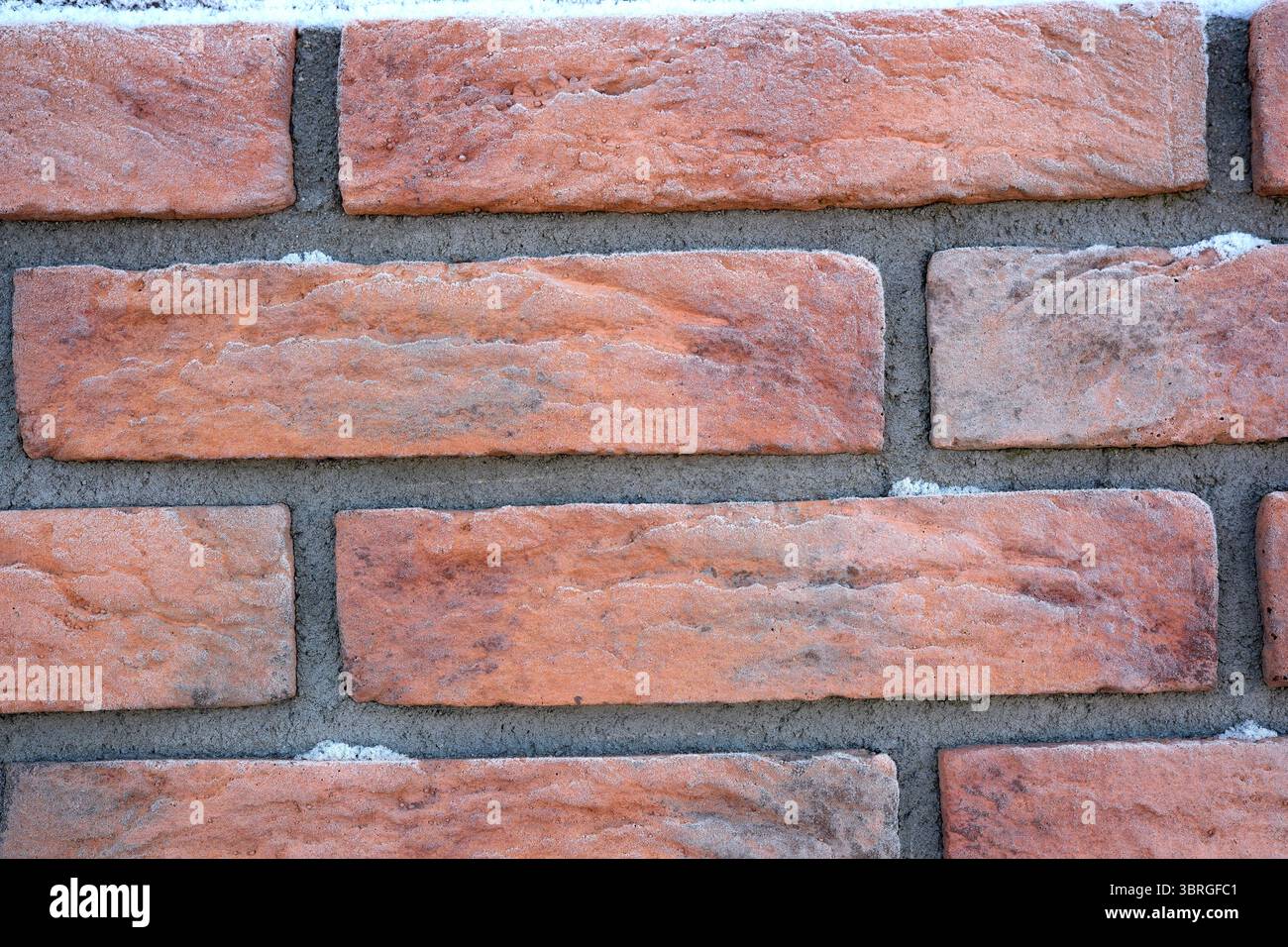 Die Nahansicht zeigt warmes, strukturiertes Ziegelwerk mit subtilen Farbvariationen. Stockfoto