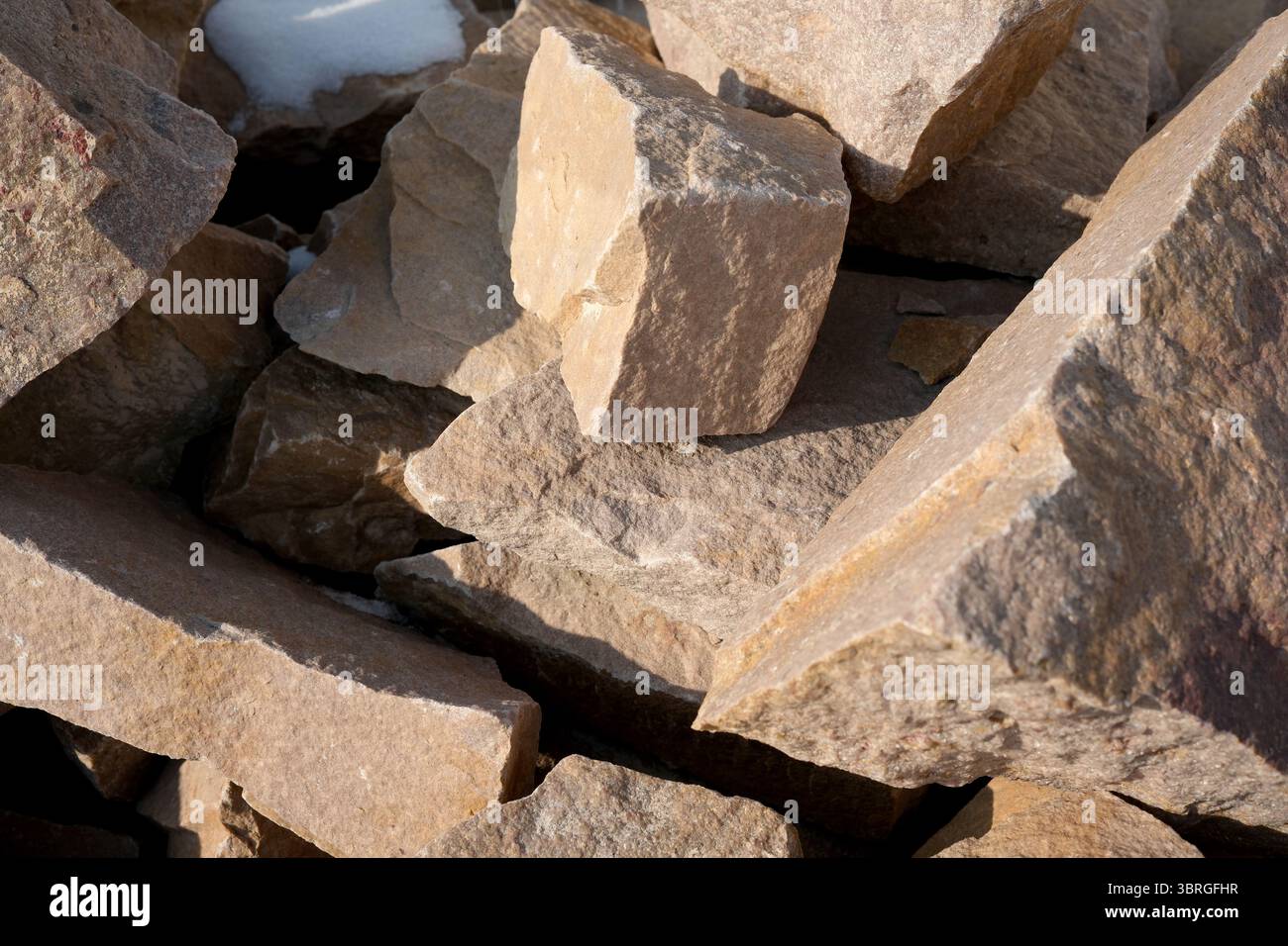 Sonnenlicht hebt die einzigartigen Texturen verwitterter Steine auf einem Stapel hervor. Stockfoto