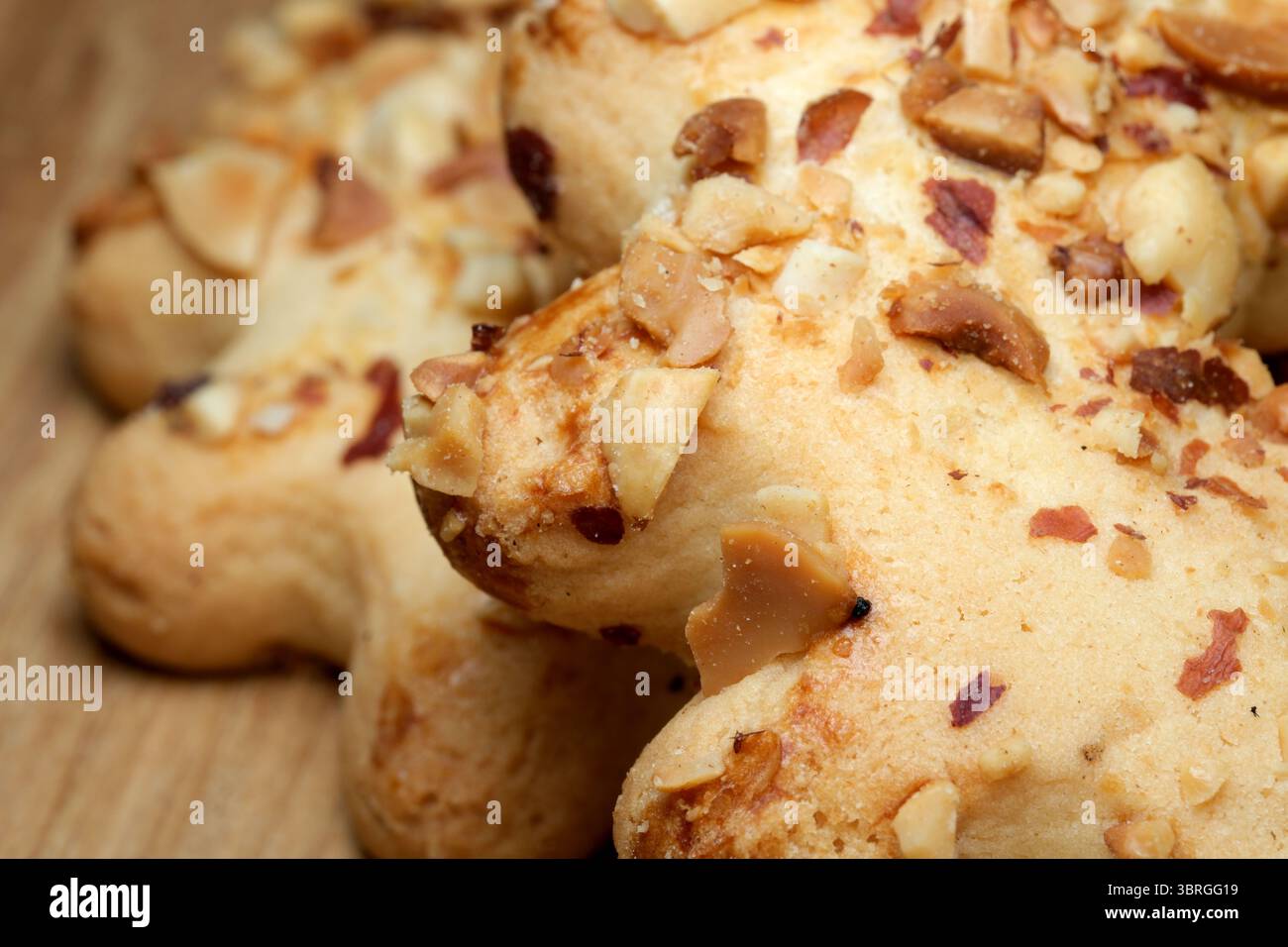 Frisch gebackene Leckereien mit knusprigen Nüssen ruhen auf einer Holzarbeitsfläche, die Wärme und einladende Aromen verströmen. Ein wunderbarer Moment in einem belebten Kitc Stockfoto