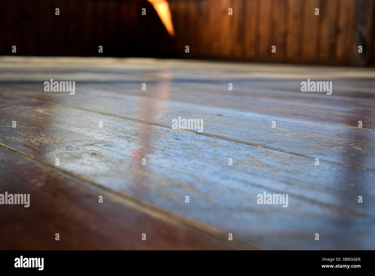 Warmes Sonnenlicht tanzt auf einem verwitterten Holzboden und schafft eine ruhige Atmosphäre. Stockfoto