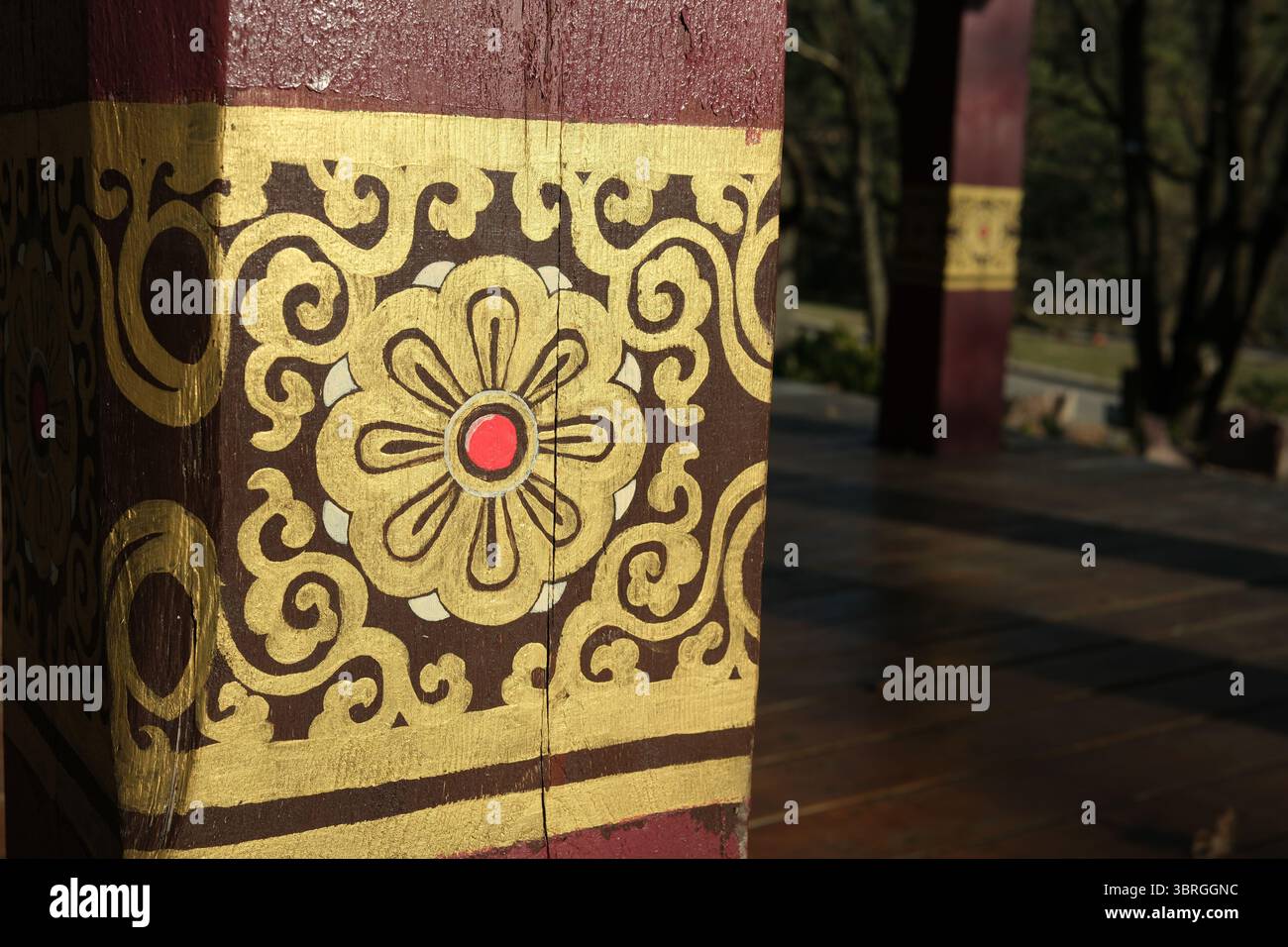 Komplexe goldene Motive erwecken eine Holzsäule in der ruhigen Umgebung der Natur zum Leben. Stockfoto