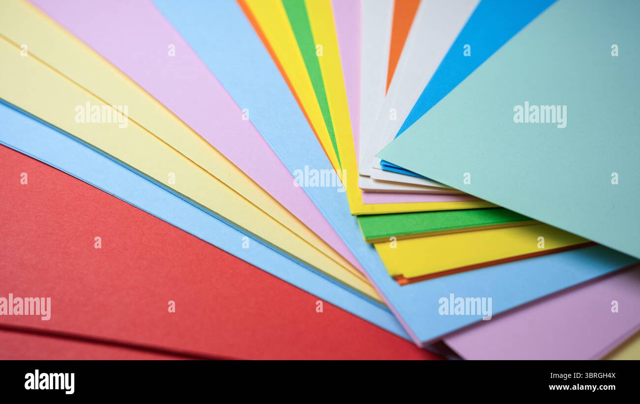 Bunte Papiere wurden aufgefächert und laden zum künstlerischen Ausdruck und Design ein. Stockfoto