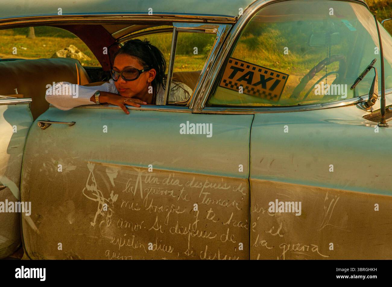 Schöne kubanische Frau denkt über das Leben in einem klassischen amerikanischen Auto, das als Taxi benutzt wird, nach Guanabo, Playas del Este, Havanna, Kuba. © Kraig Lieb Stockfoto