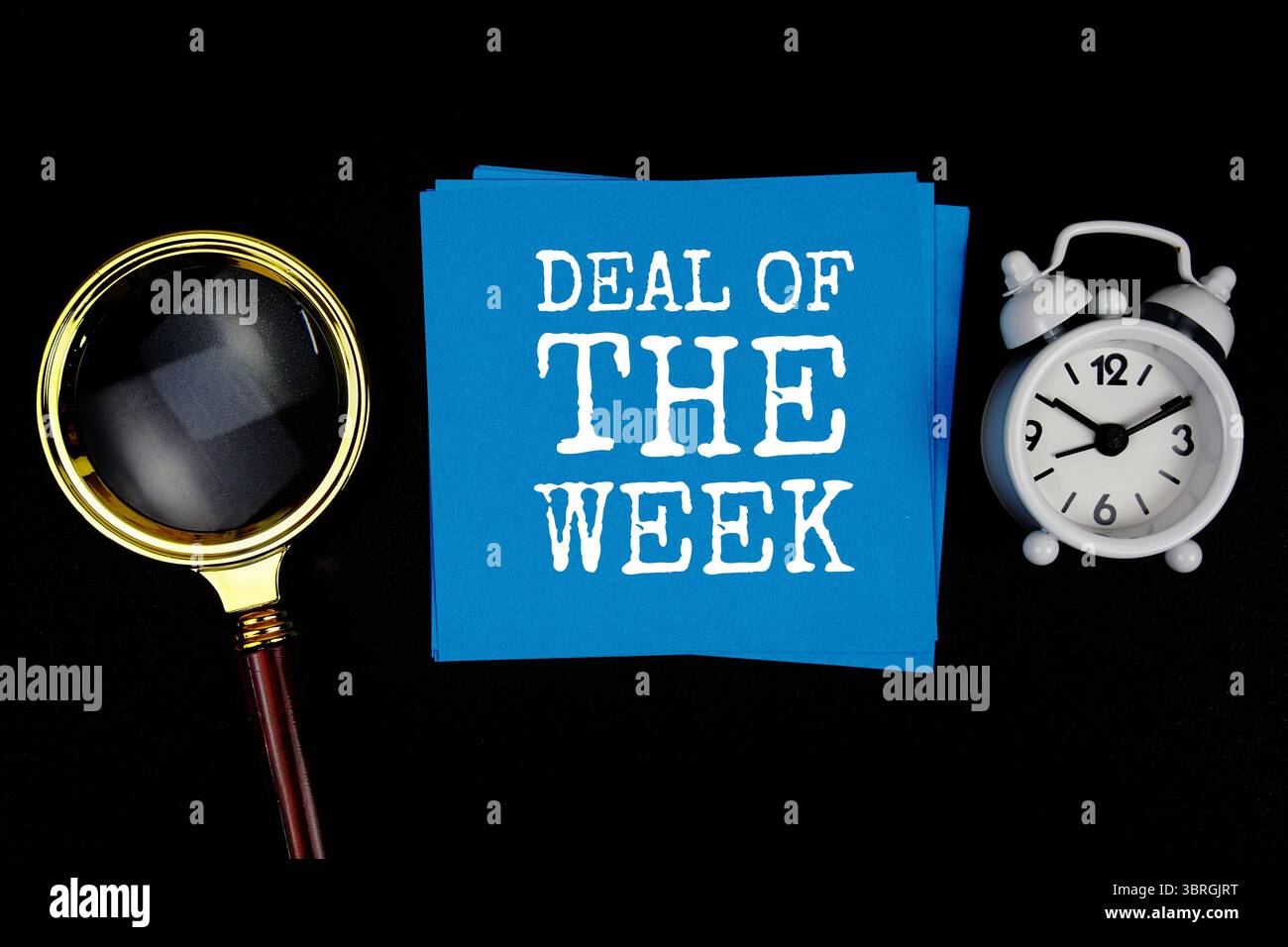 Text zum Angebot der Woche auf Haftnotiz mit Vergrößerungsglas und Wecker auf schwarzem Hintergrund Stockfoto