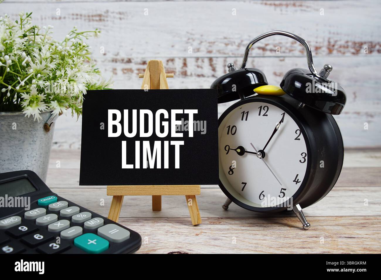 Budgetbegrenzungstext mit Wecker und Taschenrechner auf hölzernem Hintergrund Stockfoto