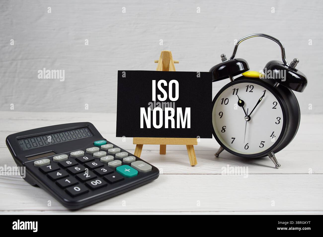 ISO-NORMTEXT mit Wecker auf hölzernem Hintergrund Stockfoto