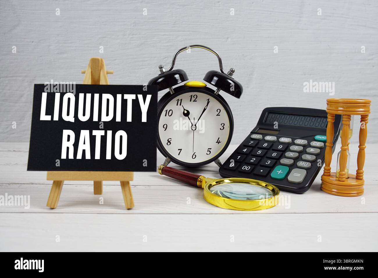 Liquiditätsverhältnis Text mit Wecker und Rechner auf hölzernem Hintergrund Stockfoto