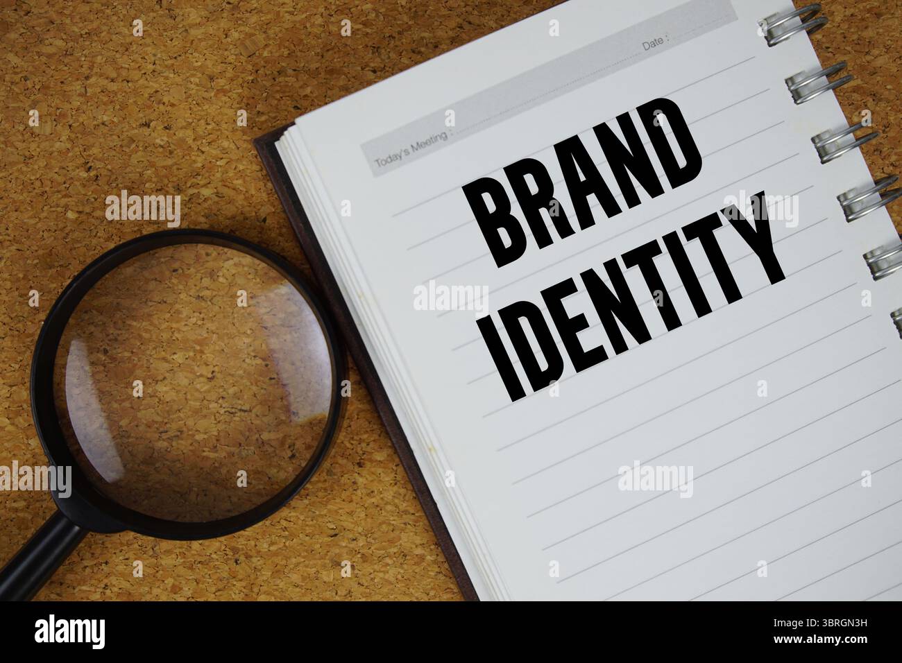 Text der Markenidentität auf Notizbuchpapier mit Lupe geschrieben Stockfoto