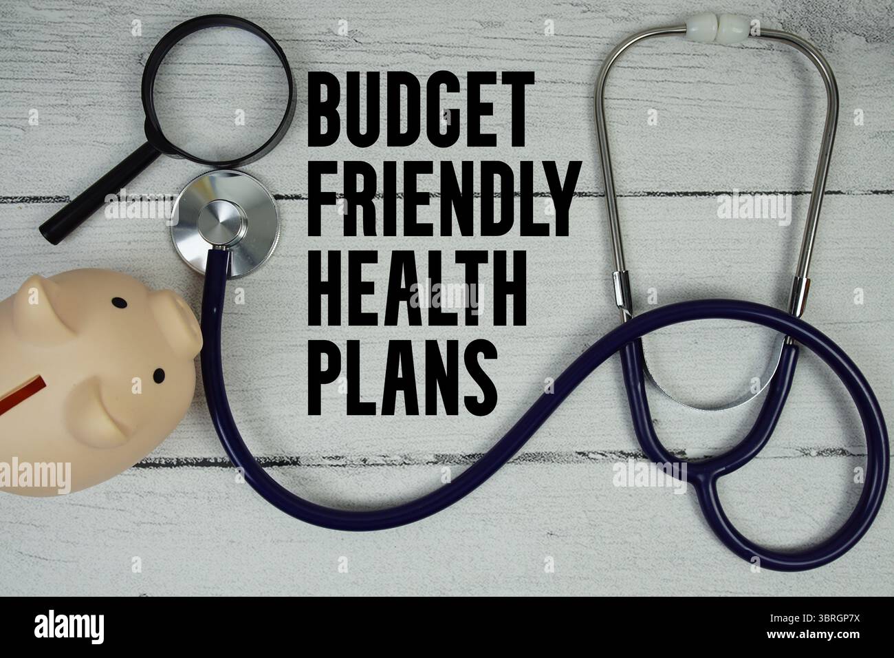 Budget-freundlicher Gesundheitspläne Text mit Stethoskop und Lupe auf hölzernem Hintergrund Stockfoto