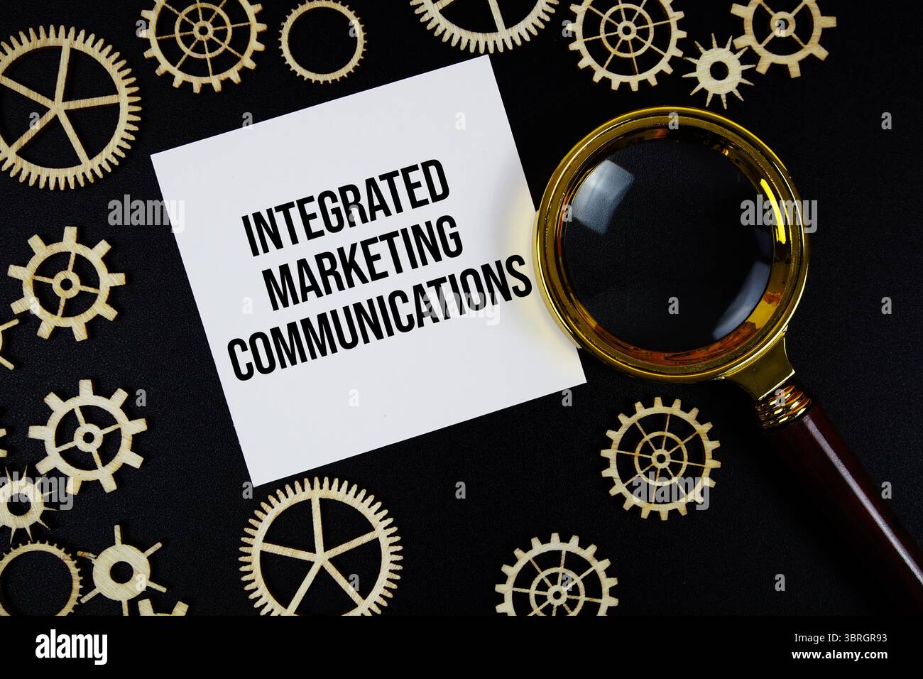 Integrierter Text für Marketingkommunikation (IMC) mit Vergrößerungsglas auf schwarzem Hintergrund Stockfoto