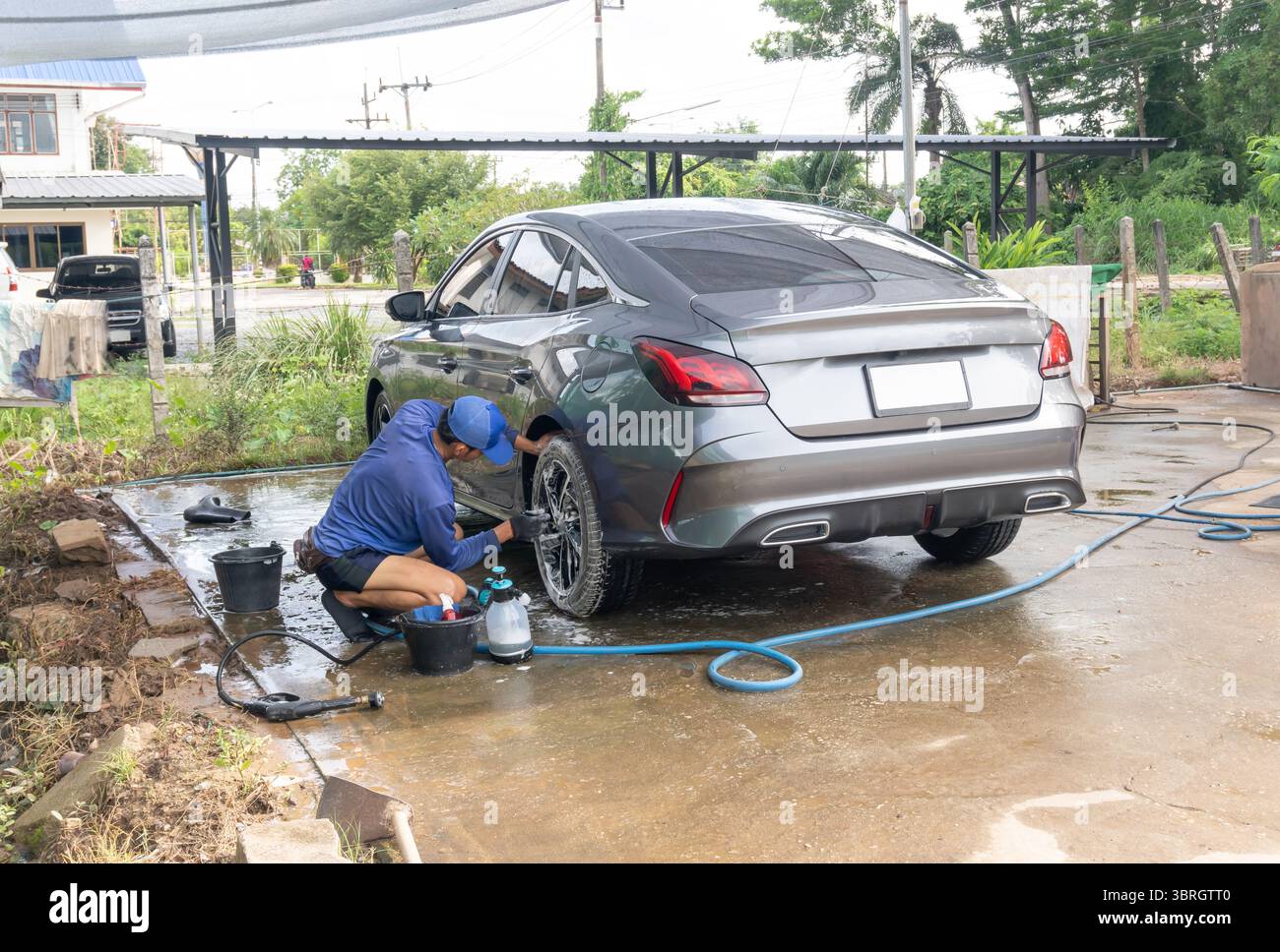 Autowaschanlage oder Autoreiniger wäscht eine graue Sportlimousine im Car Care-Zentrum. Stockfoto