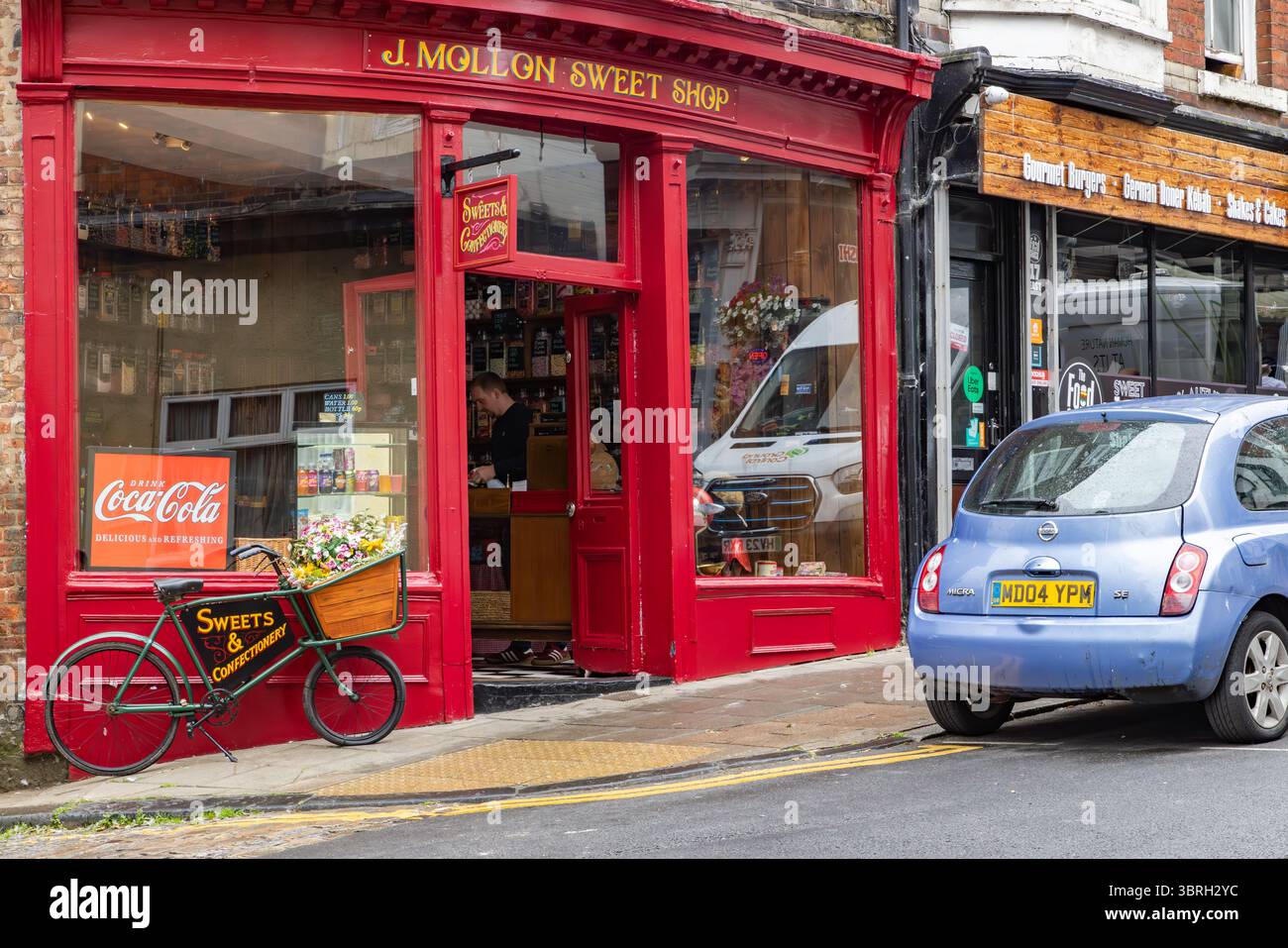 Traditionelles Süßwarengeschäft in Scarborough, North Yorkshire, mit Ladenbesitzern im Inneren und Vintage Coca-Cola-Werbung, die die britische Retail-Tradition repräsentiert Stockfoto
