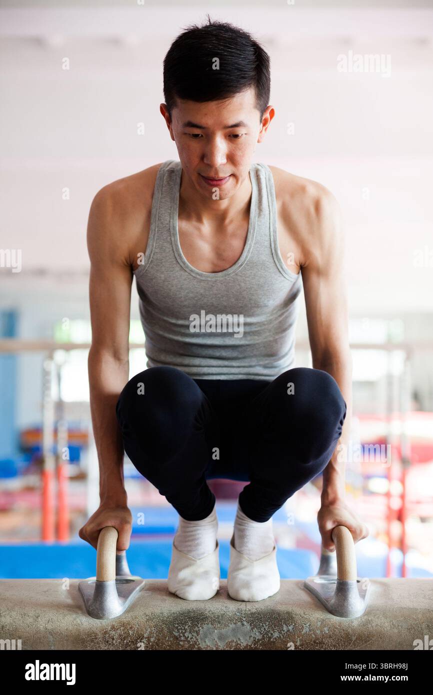 Junger Mann, der gymnastische Elemente auf dem Pommel-Pferd ausführt Stockfoto