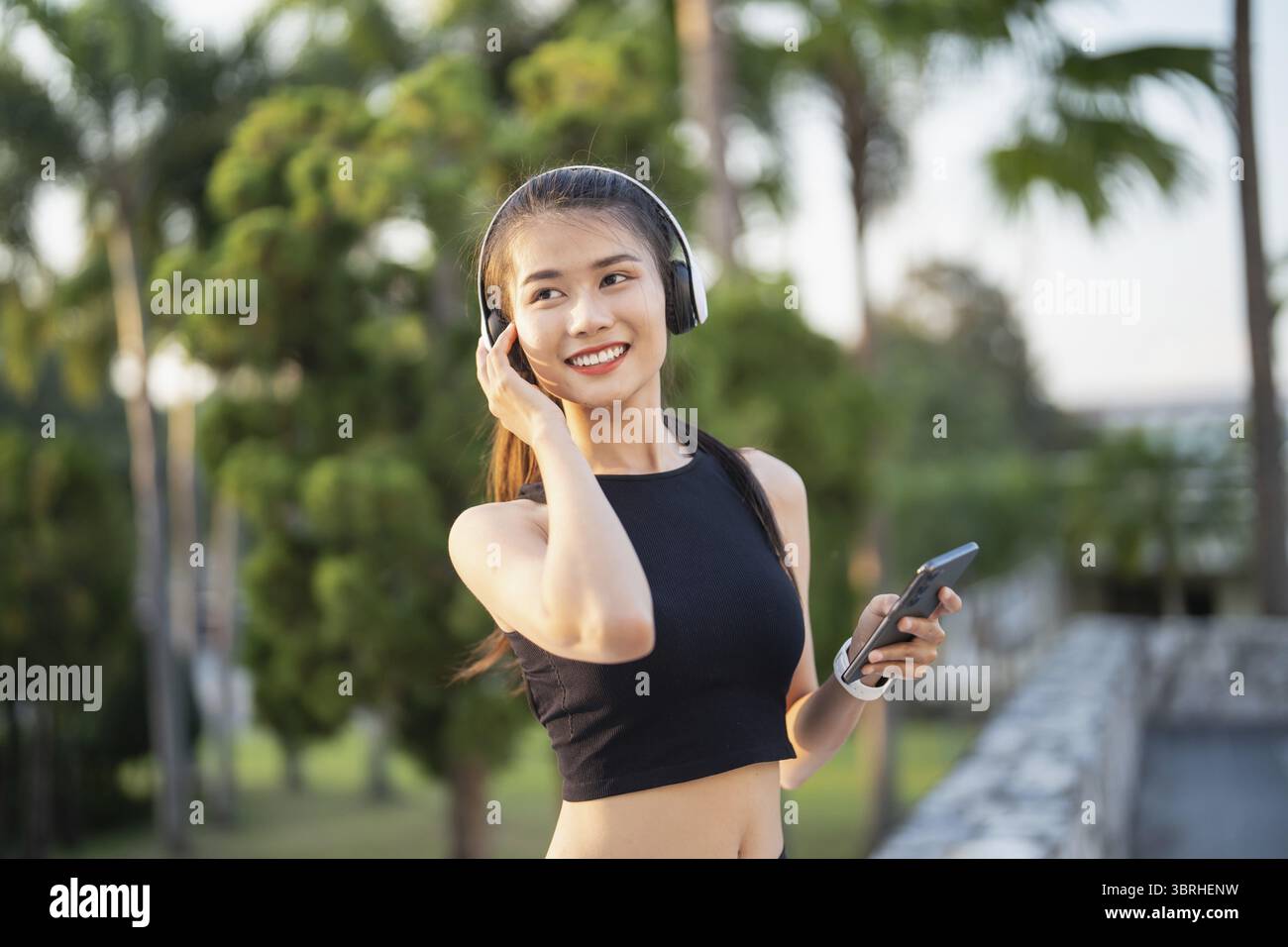 Happy Active Healthy asian Woman hört Musik mit Kopfhörern für geistige Gesundheit Hören von Audio für Laufen Inspiration Stockfoto