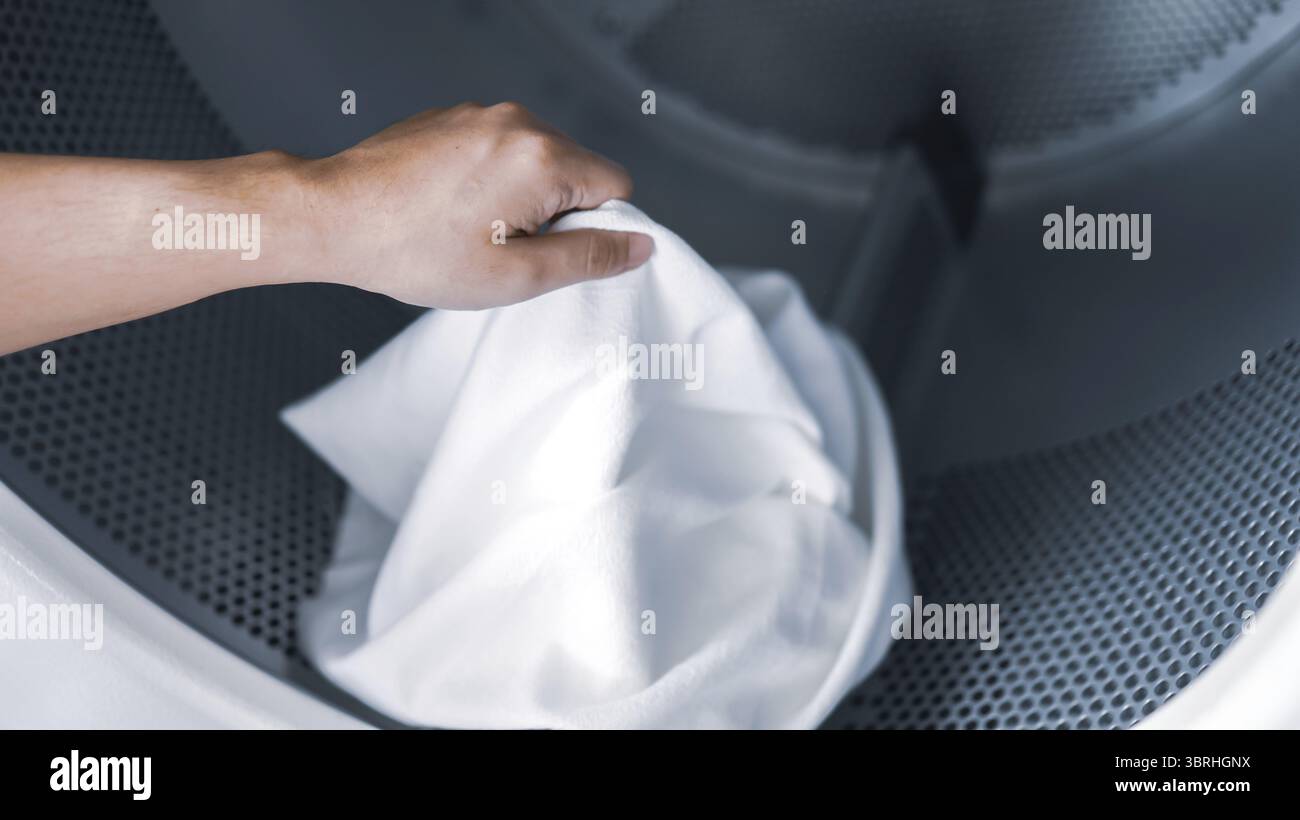 Hausmann mit Korb und schmutziger Wäsche gewaschene Kleidung im Waschraum. Waschmaschine im Wäschereigeschäft Konzept Stockfoto