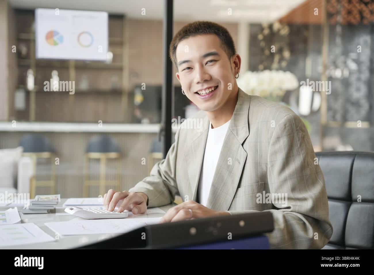 Lächelnder junger asiatischer Geschäftsmann im modernen Büro. Gutaussehender asiatischer Mann glücklich und freundlich während der Arbeit Erfolg Job Stockfoto
