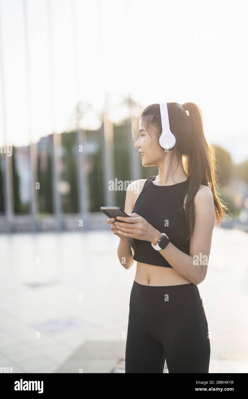 Happy Active Healthy asian Woman hört Musik mit Kopfhörern für geistige Gesundheit Hören von Audio für Laufen Inspiration Stockfoto