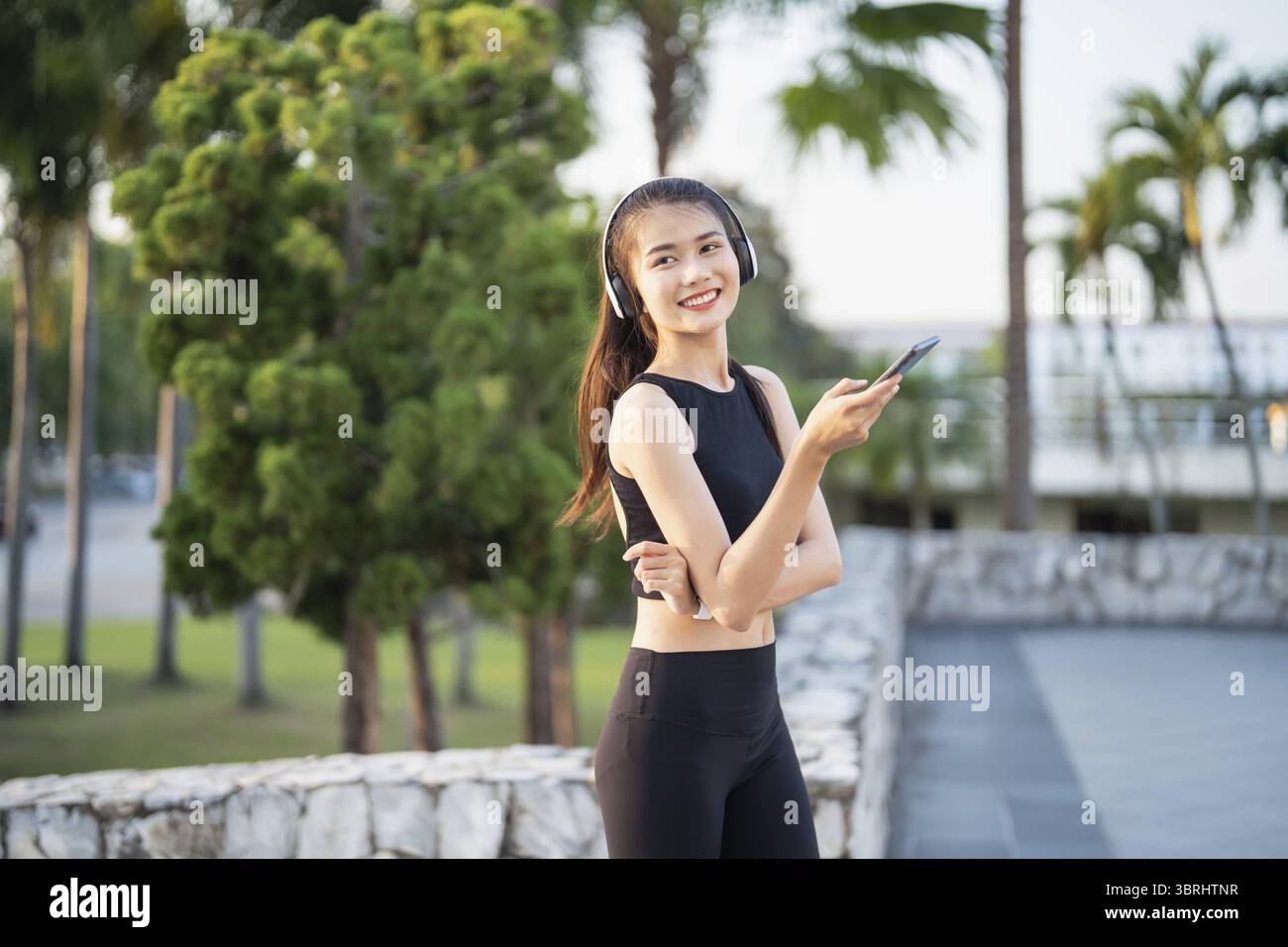 Happy Active Healthy asian Woman hört Musik mit Kopfhörern für geistige Gesundheit Hören von Audio für Laufen Inspiration Stockfoto