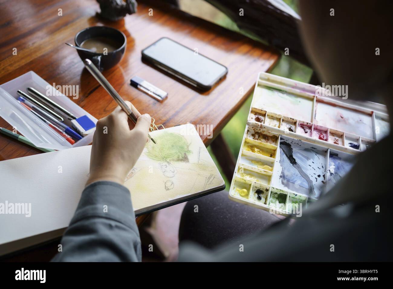 Student im Kunststudio. Hand haltender Künstler Pinsel mischen FarbÖlgemälde auf Palette Kunst Kreativität und Menschen Konzept Stockfoto