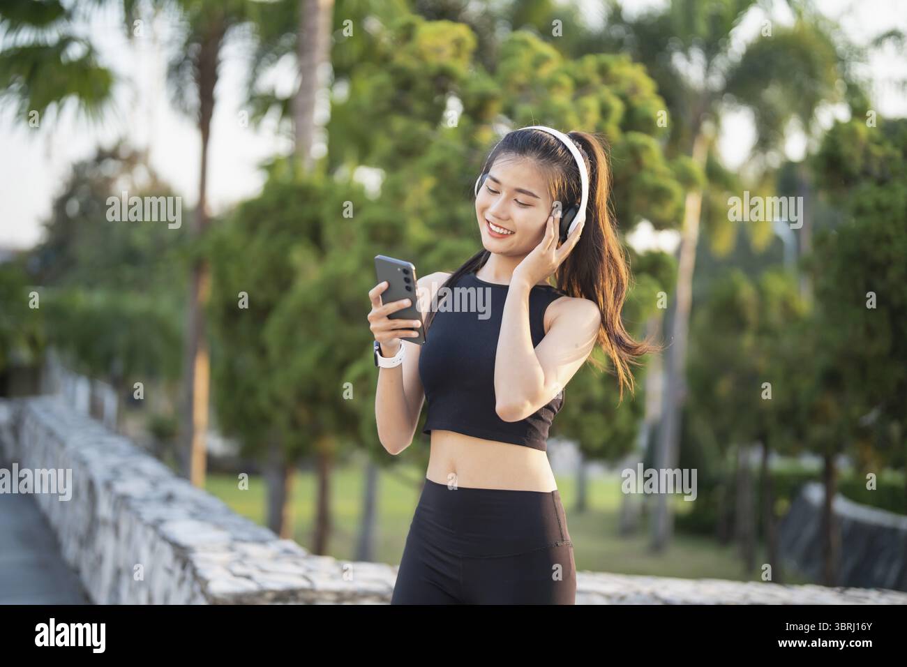 Happy Active Healthy asian Woman hört Musik mit Kopfhörern für geistige Gesundheit Hören von Audio für Laufen Inspiration Stockfoto