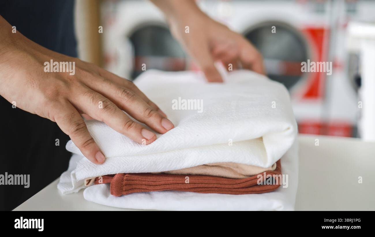 Hausmann mit Korb und schmutziger Wäsche gewaschene Kleidung im Waschraum. Waschmaschine im Wäschereigeschäft Konzept Stockfoto