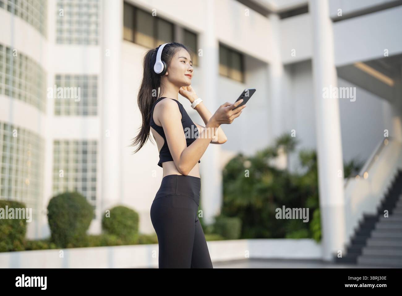 Happy Active Healthy asian Woman hört Musik mit Kopfhörern für geistige Gesundheit Hören von Audio für Laufen Inspiration Stockfoto