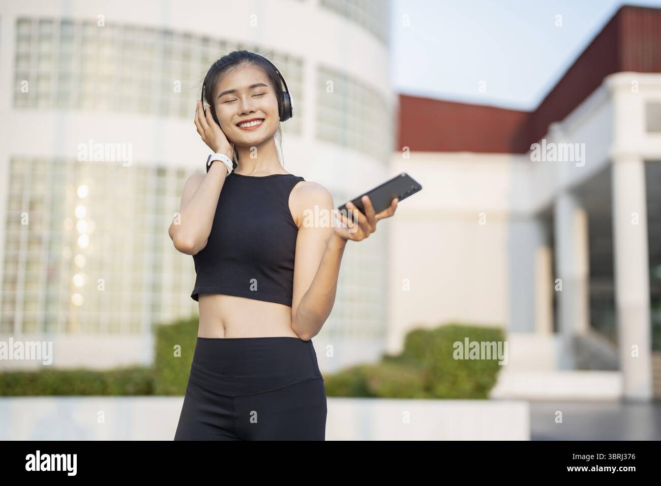 Happy Active Healthy asian Woman hört Musik mit Kopfhörern für geistige Gesundheit Hören von Audio für Laufen Inspiration Stockfoto