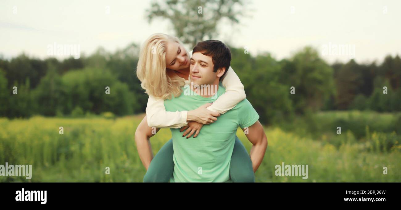 Porträt eines schönen, glücklichen, lächelnden jungen Paares, das sich in den grünen Sommerpark umarmt Stockfoto