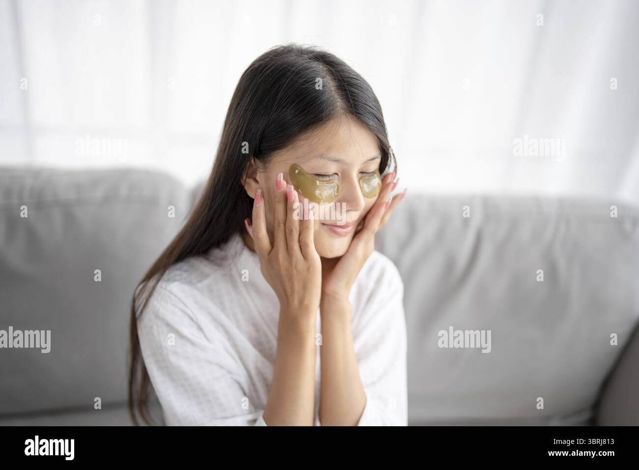 Tägliche Schönheitsroutine Asiatische Frau selbst pflegen und entspannen mit Silikon unter den Augen Flicken lächelnd glücklich mit Hautpflegeprodukt Stockfoto
