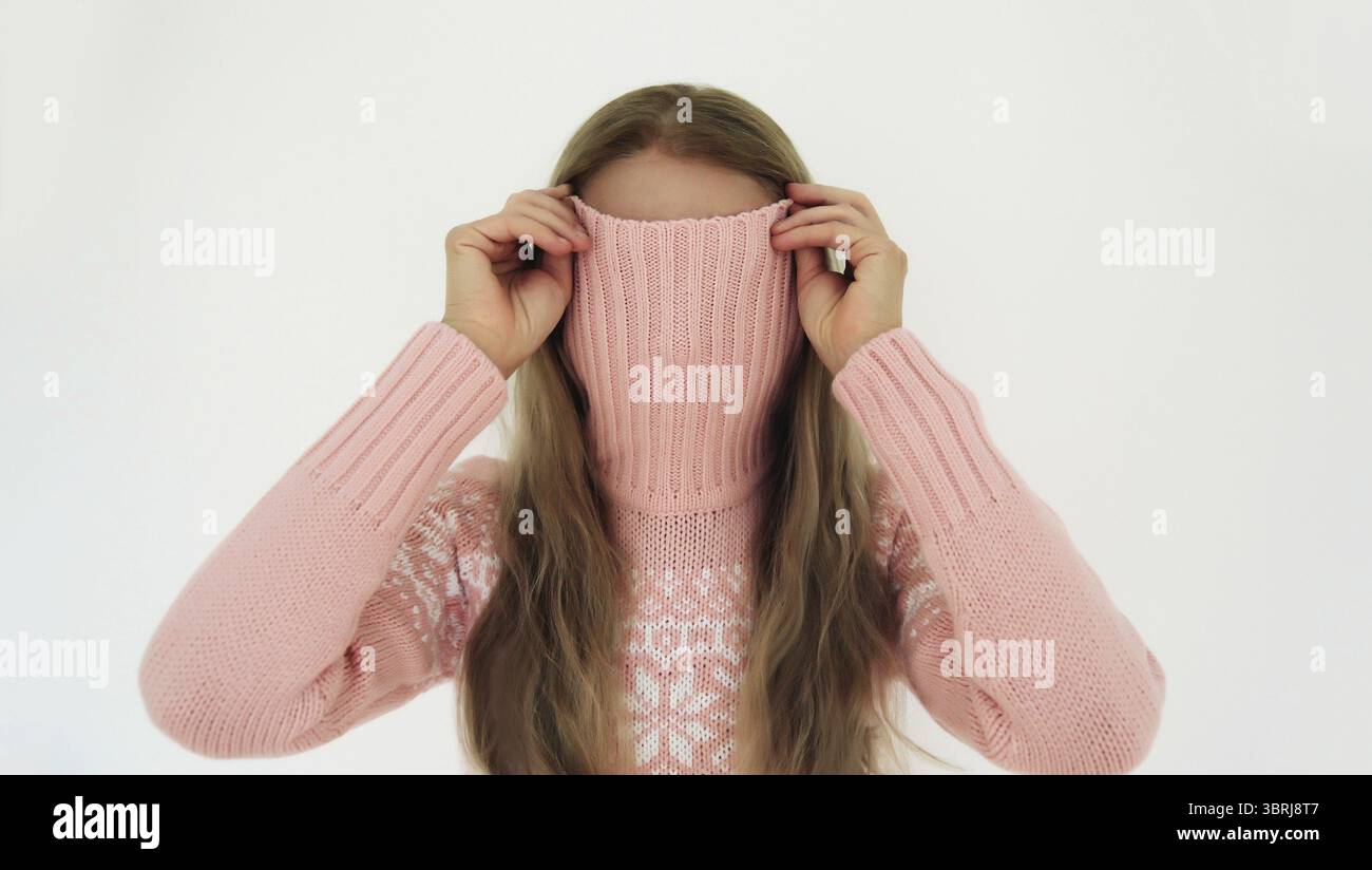Porträt einer lustigen jungen Frau, die ihr Gesicht mit einem gestrickten Pullover bedeckt oder Spaß hat, auf weißem Hintergrund zu stehen Stockfoto