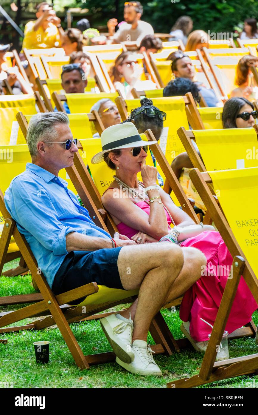 London, Großbritannien. Juli 2025. Sonniges Wetter bedeutet Strohhüte und Shorts zum Entspannen auf den Liegestühlen, um das Herrenfinale zu beobachten. Marylebones kostenloses Festival kehrt mit einer Woche Wimbledon, Street Food und Familienspaß im Portman Square Garden vom 8. Bis 13. Juli zurück. Es bietet eine Gästeküche mit Pop-ups von lokalen Favoriten, Tennis auf der Großleinwand, Kunstworkshops, eine Bar am Home House und liegt in einem der schönsten Grünflächen Londons, die selten für die Öffentlichkeit zugänglich sind. Guy Bell/Alamy Live News Stockfoto