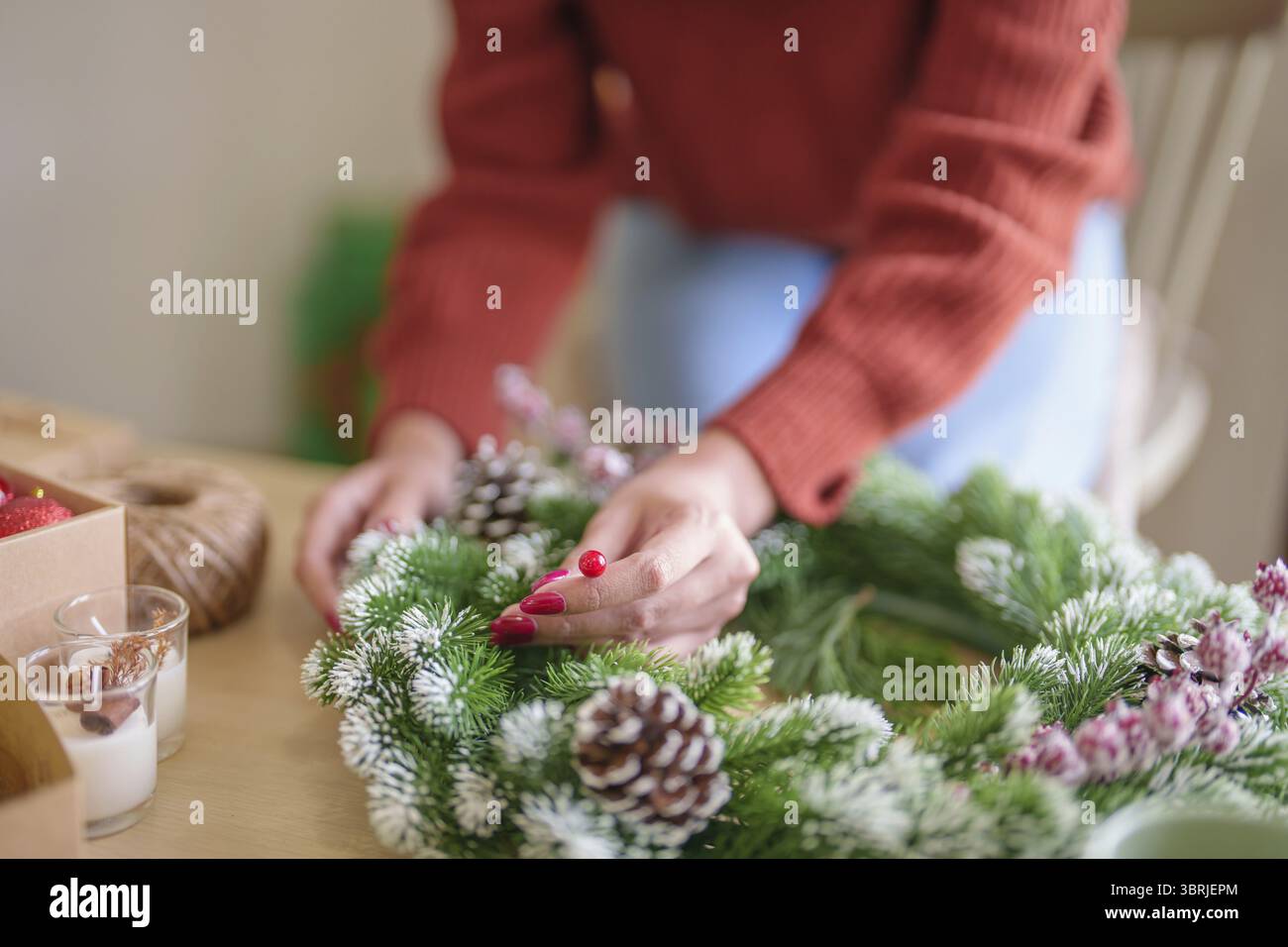 Frau, die Mistelkranz macht Weihnachtskranz Dekoration mit handgemachten DIY Winter Grün Blumenhändler Hände machen Weihnachtskranz schöne Mistel Stockfoto