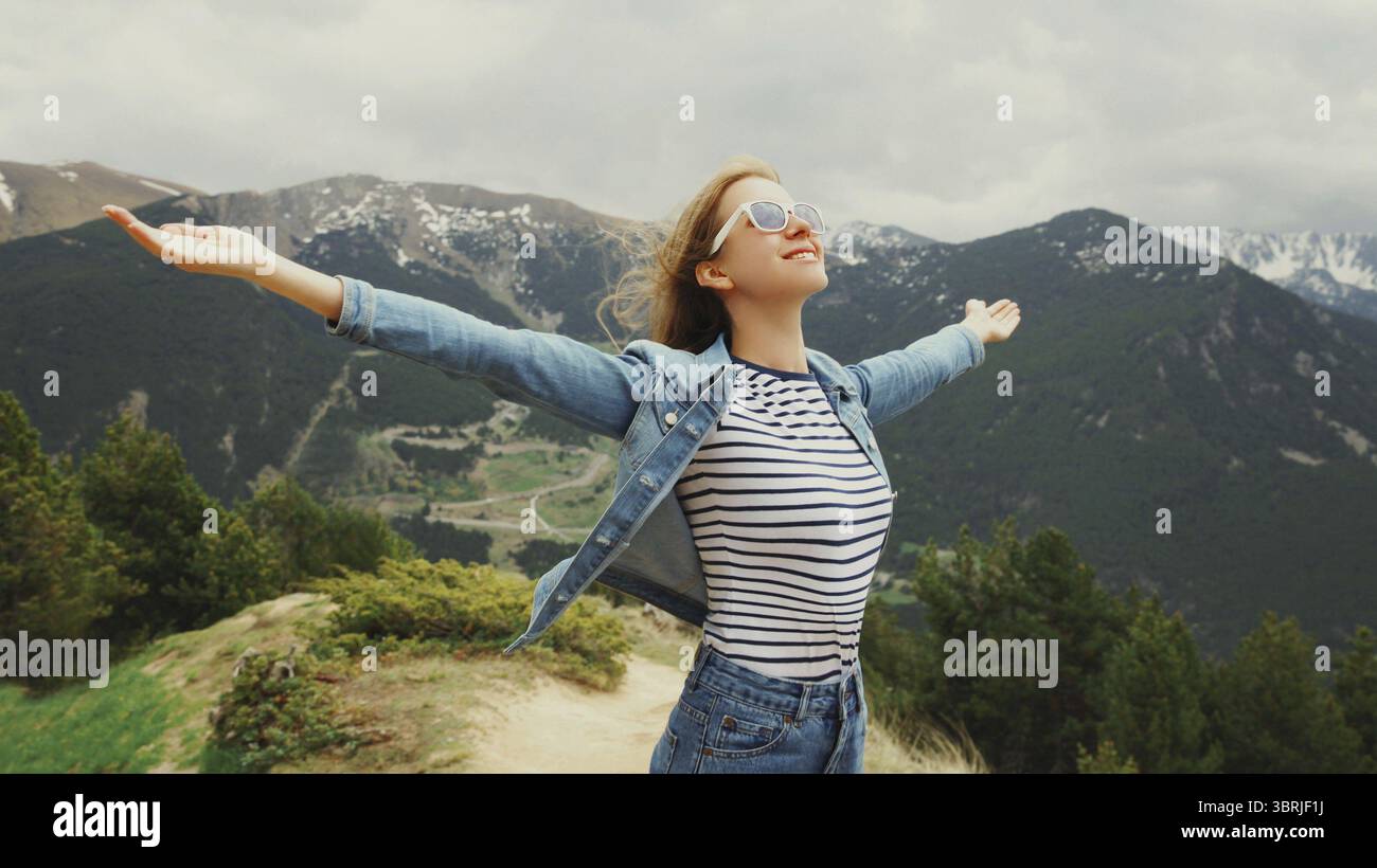 Frau, die frische Luft genießt und ihre Hände vor Andorra-Hintergrund hochhebt Stockfoto