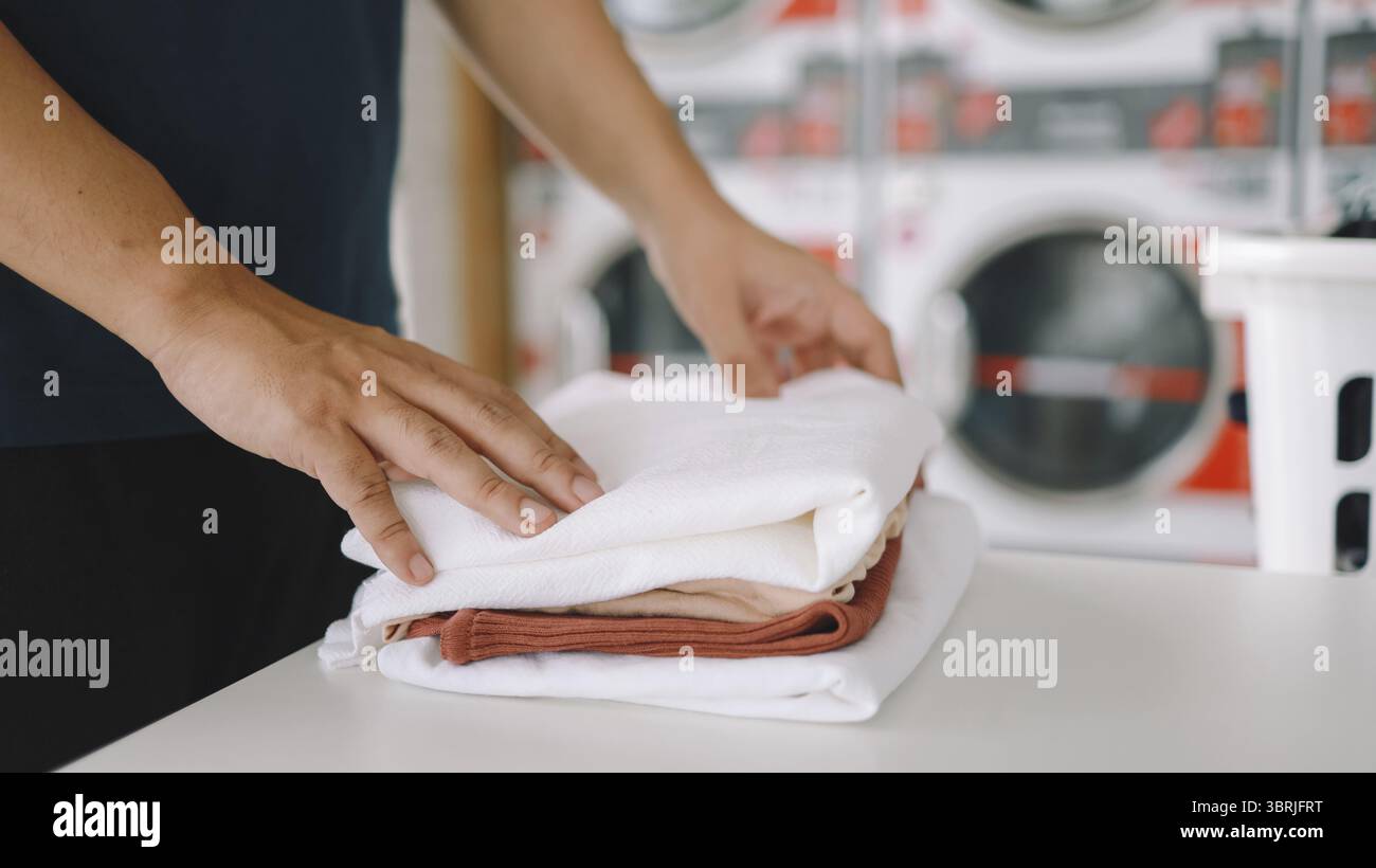 Hausmann mit Korb und schmutziger Wäsche gewaschene Kleidung im Waschraum. Waschmaschine im Wäschereigeschäft Konzept Stockfoto