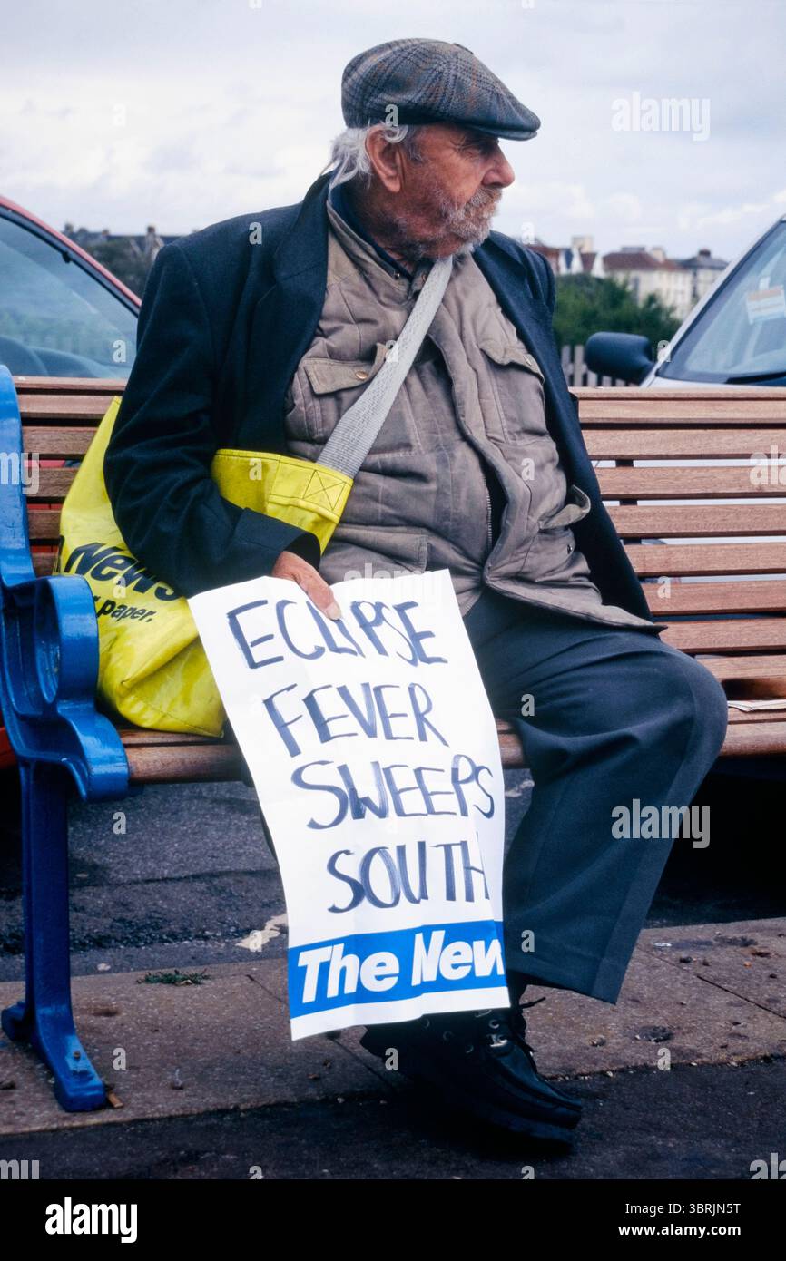 Der ältere Mann Zeitungsverkäufer saß auf der Bank am Meer und hielt ein großes handgeschriebenes Poster mit den Schlagzeilen Eklipse Fieber fegt nach Süden und bezieht sich auf die totale Sonnenfinsternis august 1999 england großbritannien Stockfoto Der ältere Mann Zeitungsverkäufer saß auf der Bank am Meer und hielt ein großes handgeschriebenes Poster mit den Schlagzeilen Eklipse Fieber fegt nach Süden und bezieht sich auf die totale Sonnenfinsternis august 1999 england großbritannien Stockfoto