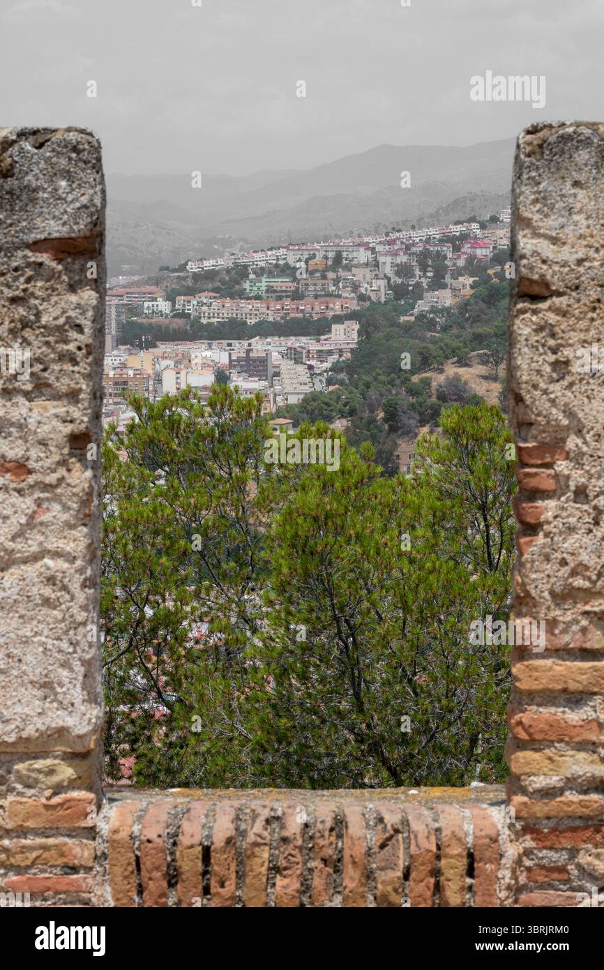 Gerahmter Blick auf Málaga Hügelviertel durch ein Steinfenster der Burgmauern von Gibralfaro Stockfoto