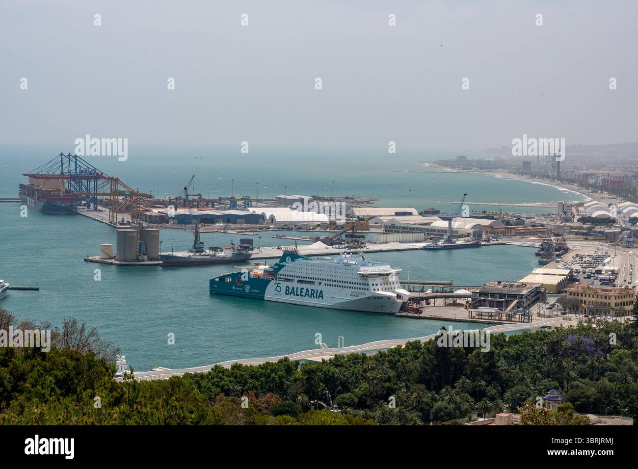 Titel: Panoramablick auf die Küste von Málaga von Gibralfaro aus mit dem Hafen, der Fähre Balearia und dem üppigen Park darunter Stockfoto