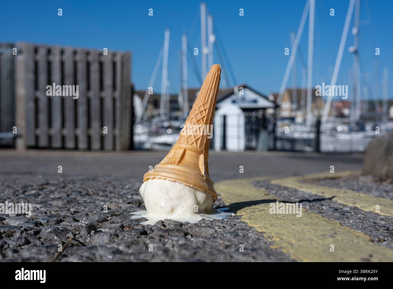Ein heruntergefallener Eiskegel schmilzt auf einer sonnigen Straße Stockfoto