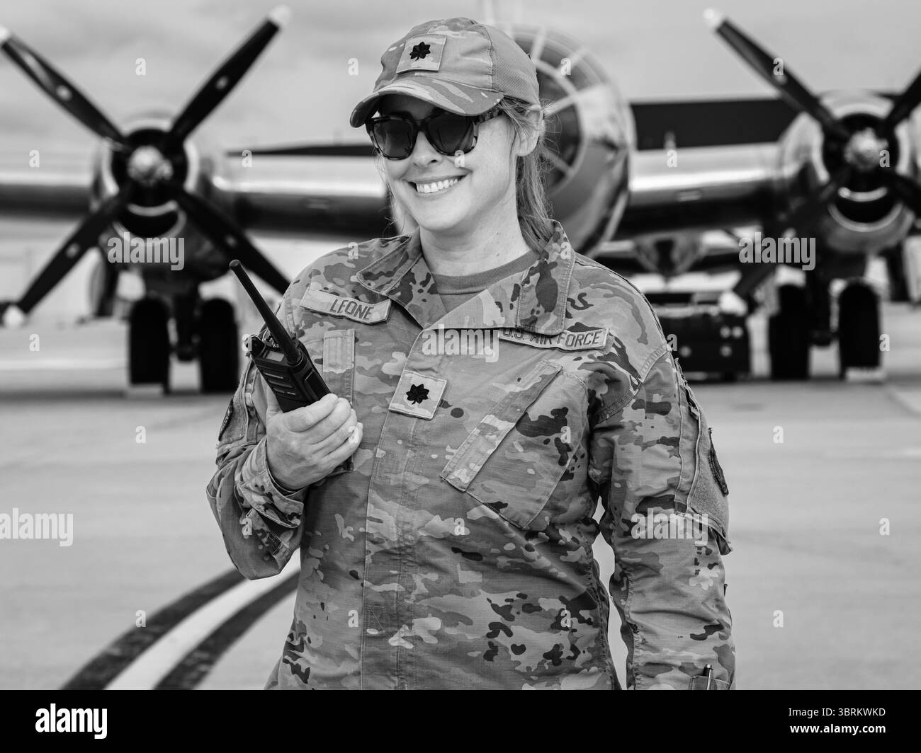 Oberleutnant Leone von der US Air Force auf der McGuire AFB Airshow, 16. Mai 2025, in Uniform mit Radio in der Hand und Oldtimer-Flugzeugen dahinter. Stockfoto