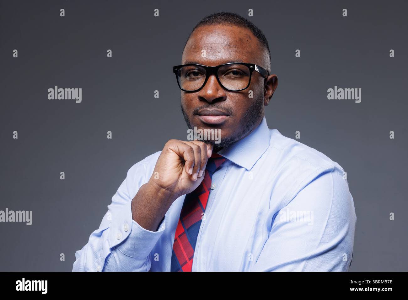Nachdenklicher afrikanischer Geschäftsmann in formellem Anzug und Brille, Symbol für Führung, Selbstvertrauen und Geschäftserfolg Stockfoto