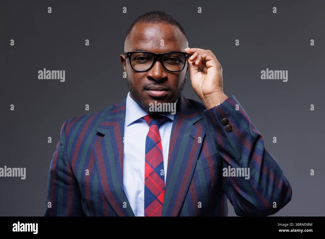Selbstbewusster afrikanischer Geschäftsmann in trendiger Brille und elegantem Anzug, der Stil und Führung in der Geschäftswelt zeigt Stockfoto
