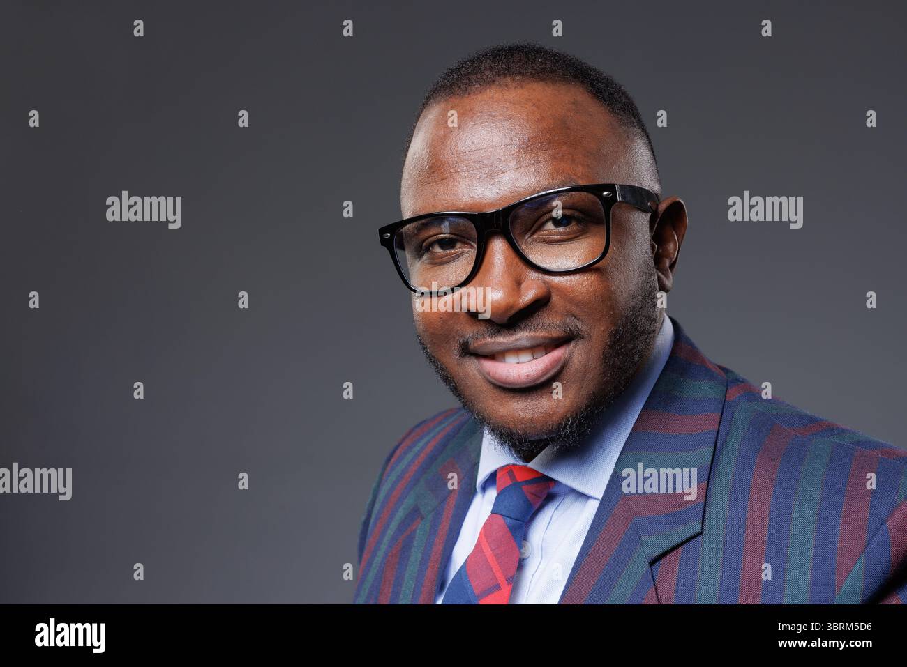 Selbstbewusster afrikanischer Geschäftsmann in stilvoller Brille und Anzug, der Erfolg, moderne Führung und professionelle Eleganz zeigt Stockfoto
