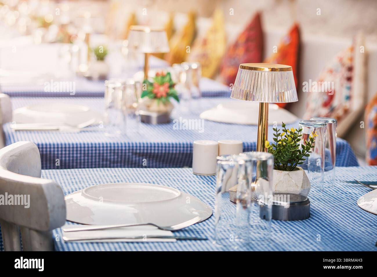 Raffiniertes Restaurant im Freien mit blau karierten Tischdecken und Ambiente-Beleuchtung für eine gemütliche und einladende Atmosphäre Stockfoto